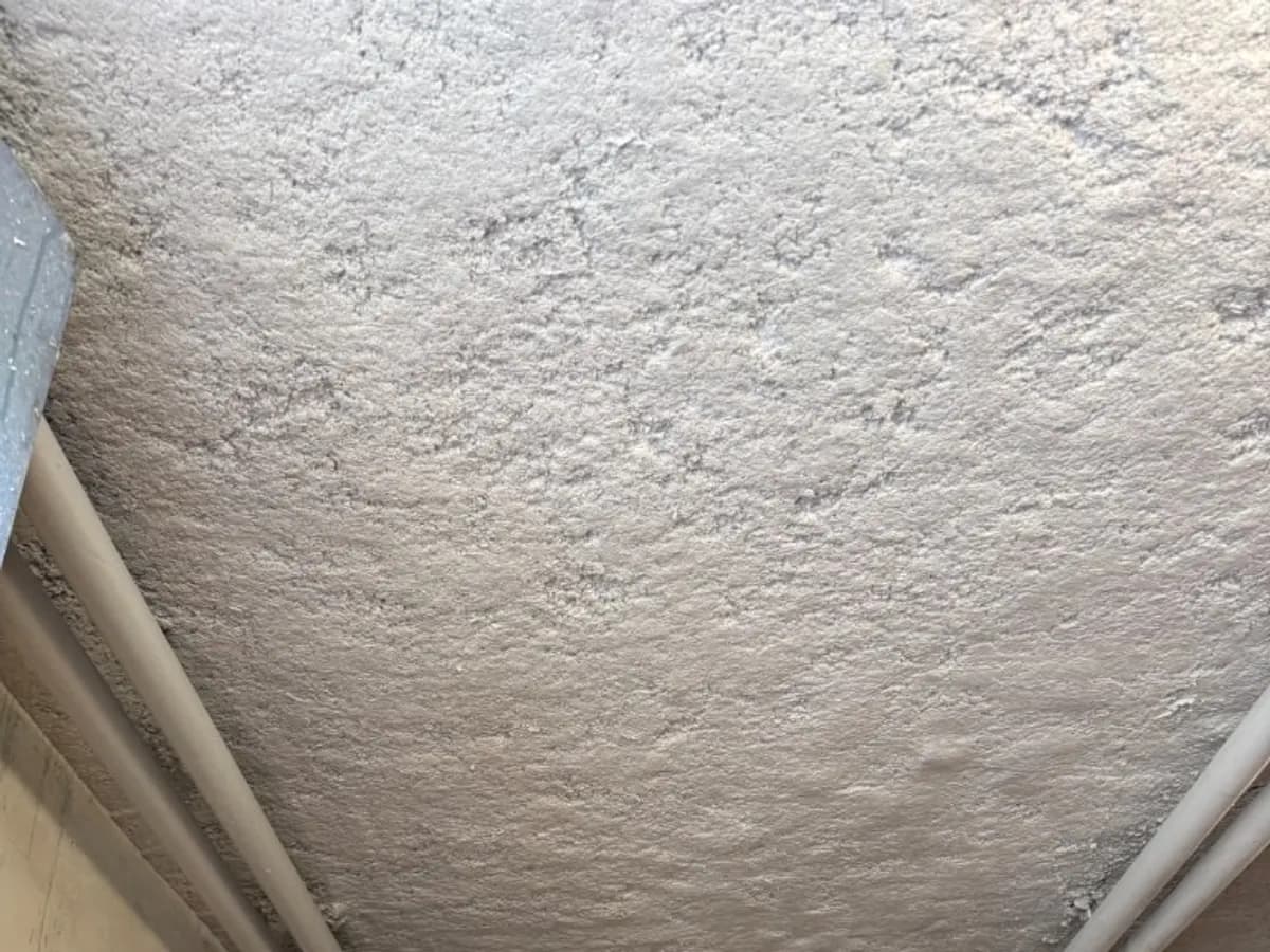 Plafond technique isolé par flocage, avec réseaux apparents